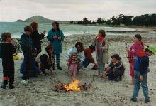 families gather around a campfire on the beach at a homeschooling camp