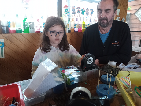 child doing a STEM challenge with man supervising and helping